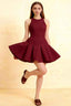 Burgundy round neck sleeveless Cheryl skater mini dress in crepe, twirling front view for homecoming or cocktail party.