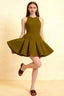 Olive green Cheryl skater dress for homecoming, featuring a flattering round neckline and pleated mini skirt, modeled with heels against a neutral studio background.