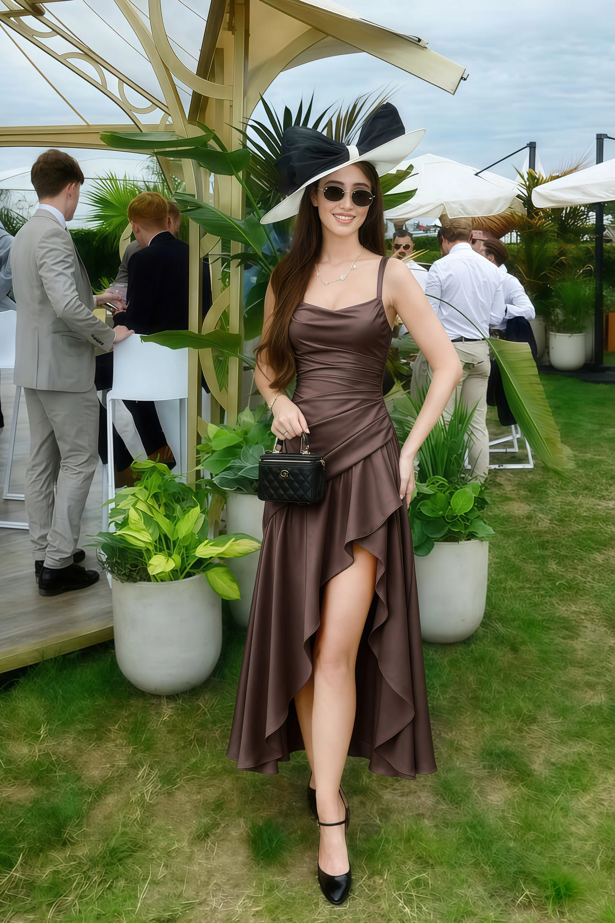 The LVLVS Ada chocolate brown midi dress worn on a lawn at an outdoor gathering, styled with a hat, sunglasses and a black handbag.