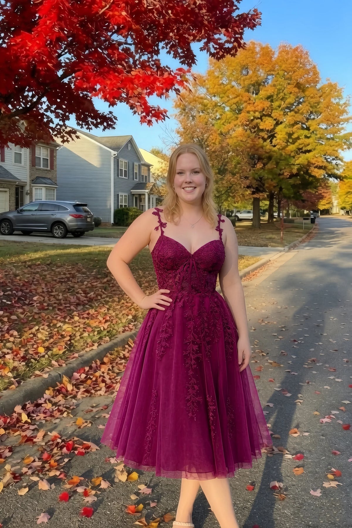 Front view of the LVLVS Adeline burgundy midi dress on an autumn street, with red and yellow leaves in the background.
