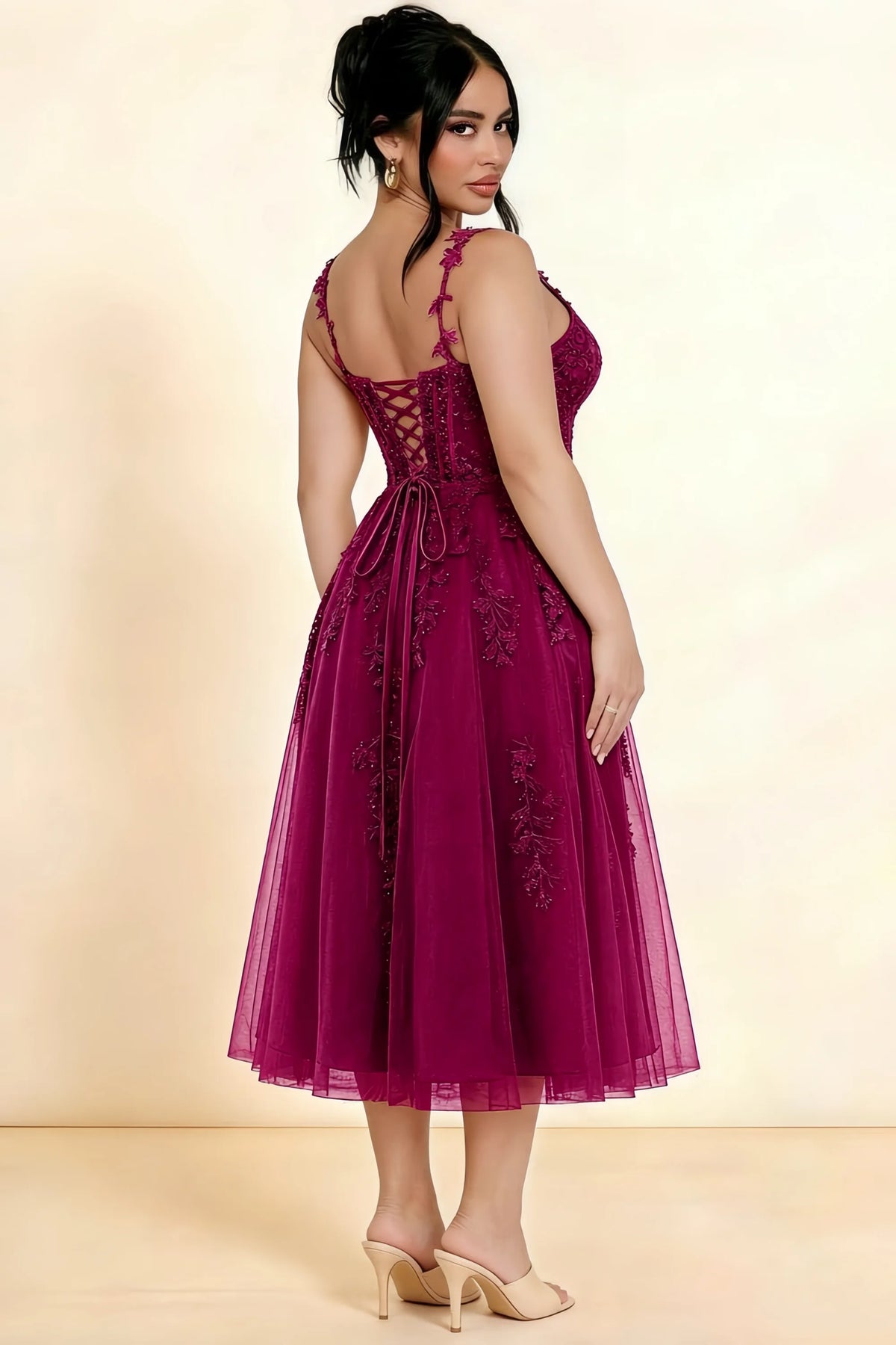 Rear three-quarter view of a model wearing the LVLVS Adeline burgundy midi dress, showing the lace-up back and layered midi skirt.
