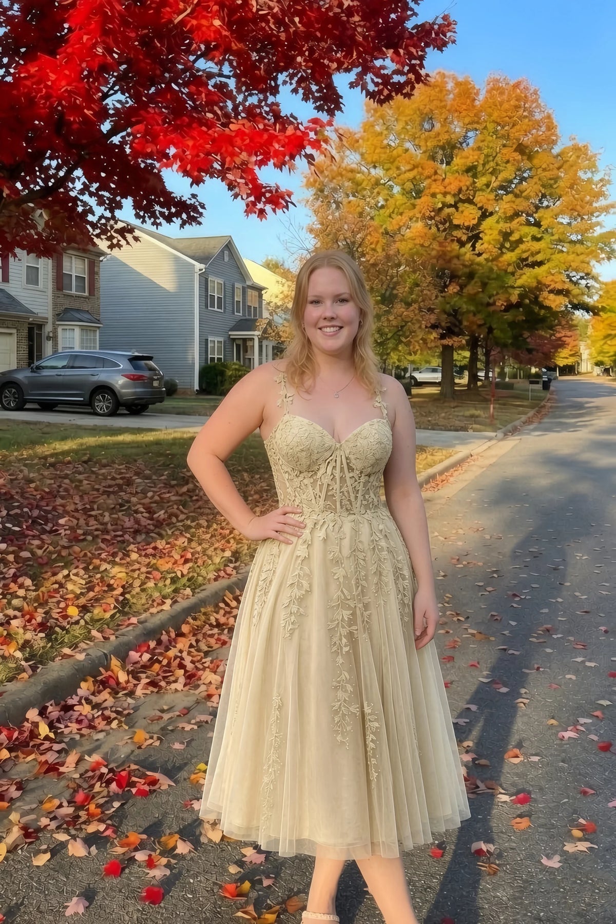 Front view of the LVLVS Adeline champagne midi dress on an autumn street, with red and yellow leaves in the background.