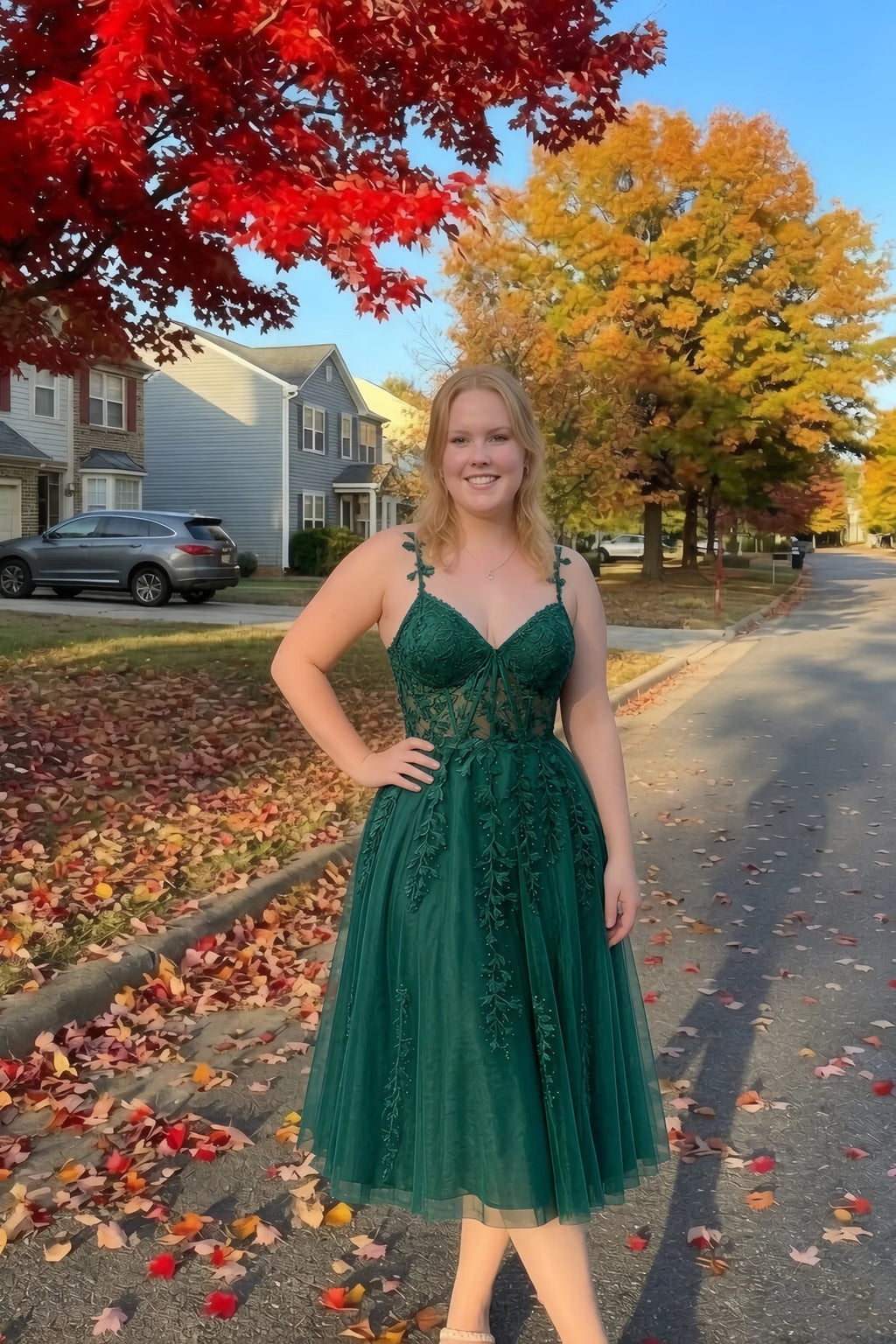 Front view of the LVLVS Adeline dark green midi dress on an autumn street, with red and yellow leaves in the background.