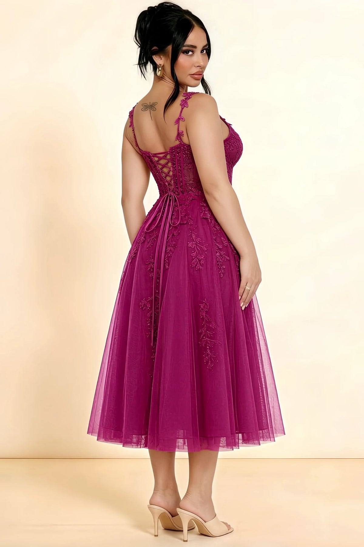 Rear three-quarter view of a model wearing the LVLVS Adeline fuchsia midi dress, showing the lace-up back and layered midi skirt.