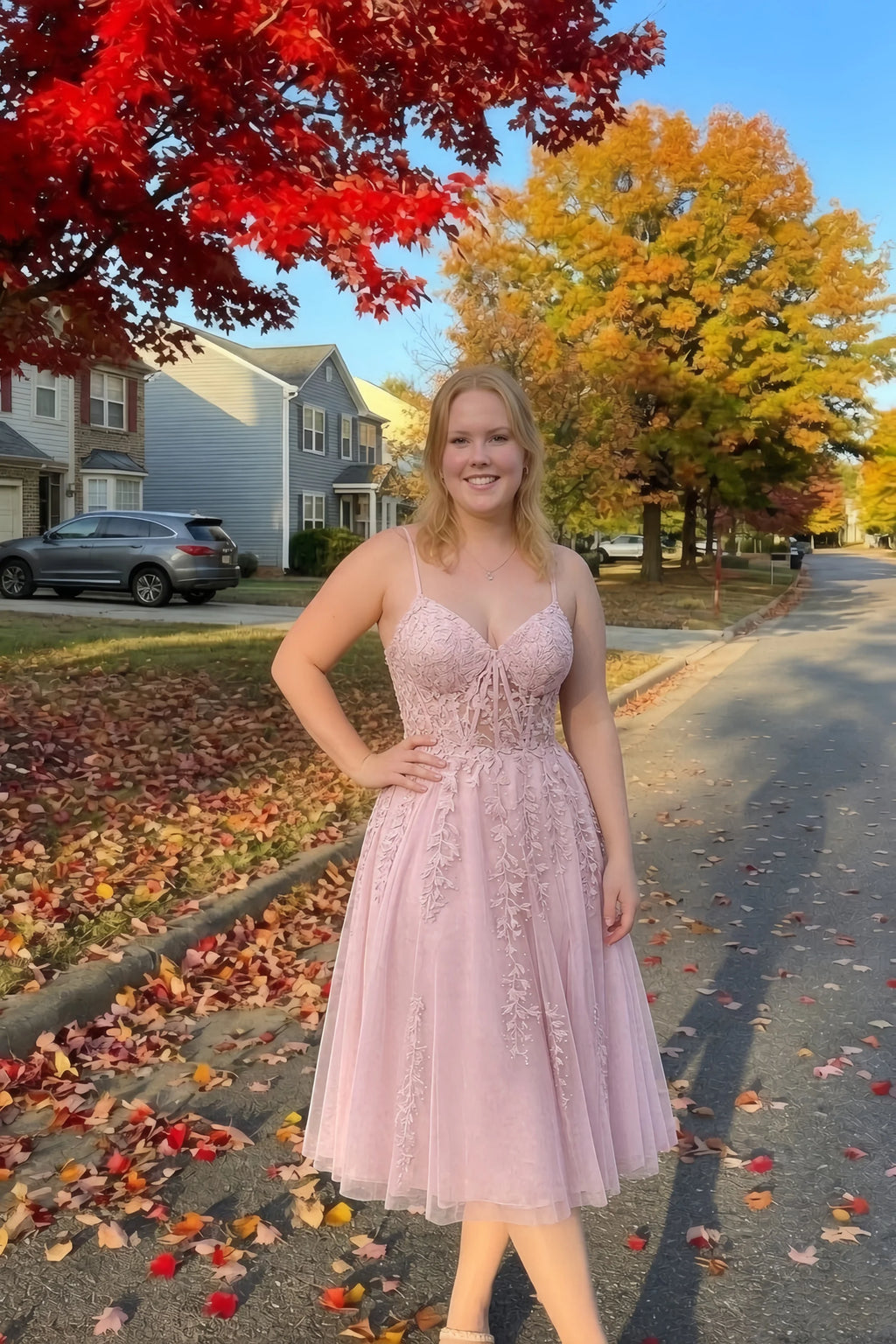 Front view of the LVLVS Adeline light pink midi dress on an autumn street, with red and yellow leaves in the background.