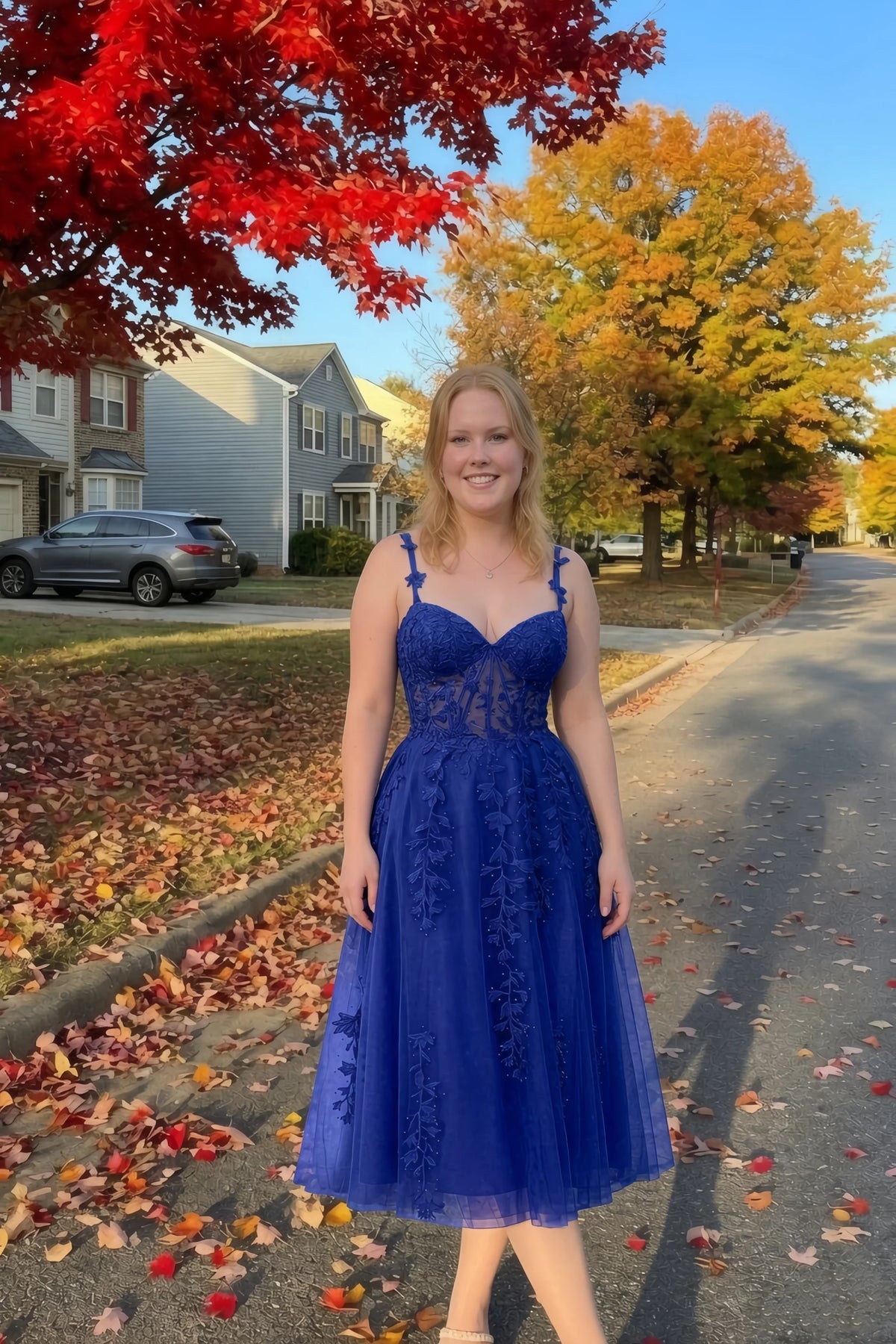 Front view of the LVLVS Adeline royal blue midi dress on an autumn street, with red and yellow leaves in the background.