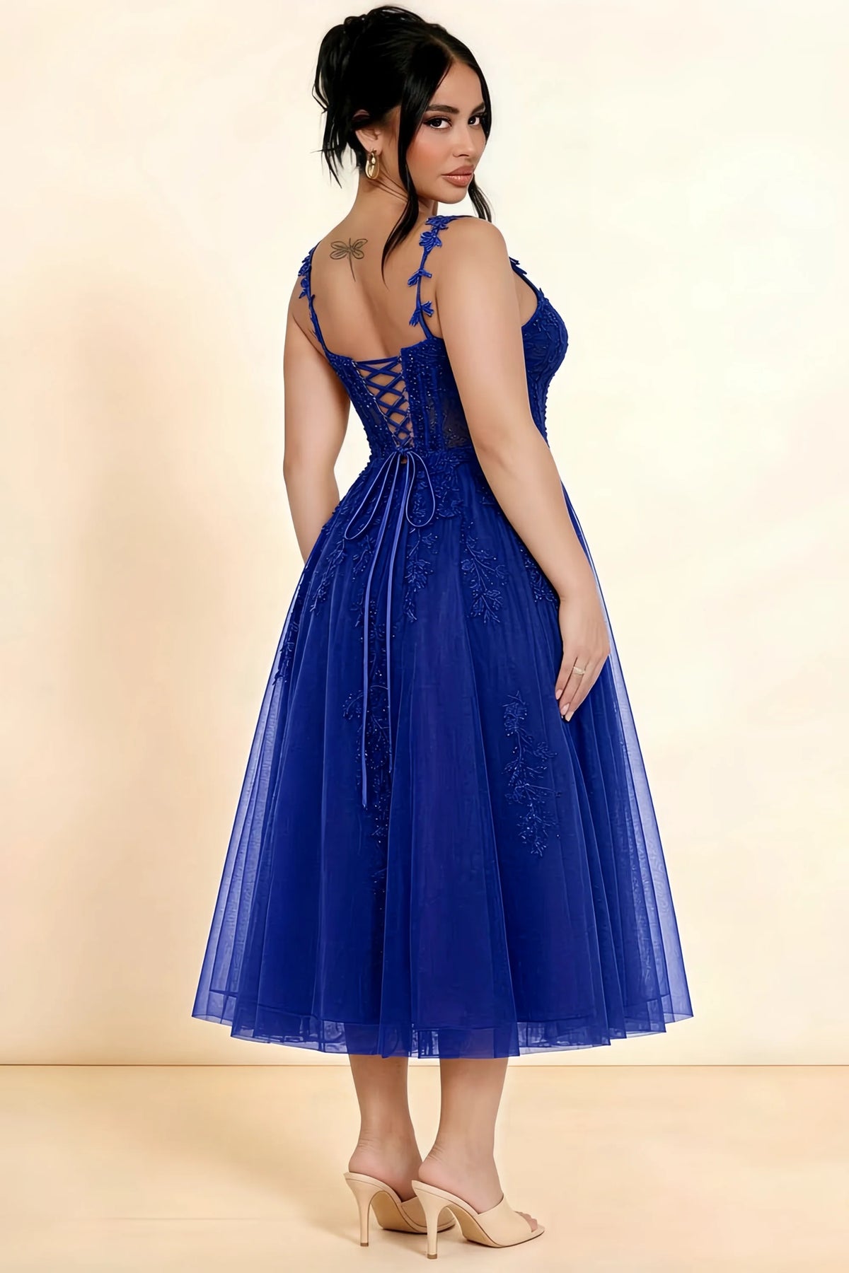 Rear three-quarter view of a model wearing the LVLVS Adeline royal blue midi dress, showing the lace-up back and layered midi skirt.