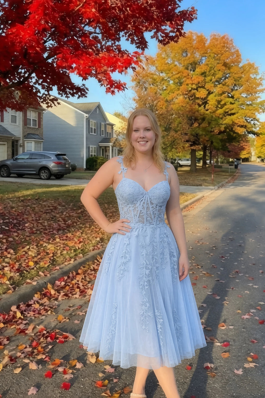 Front view of the LVLVS Adeline sky blue midi dress on an autumn street, with red and yellow leaves in the background.