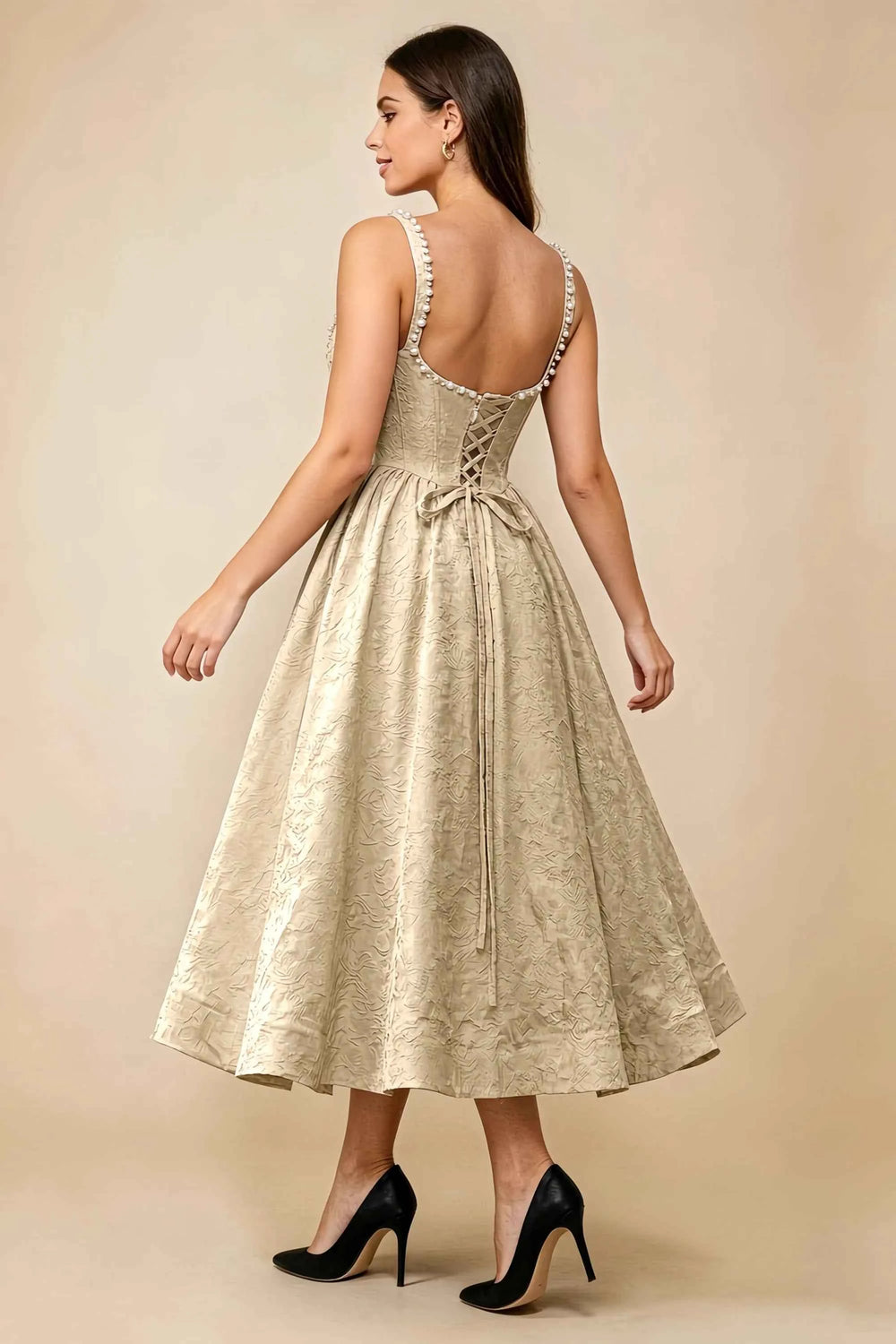 Translation missing: en.Rear three-quarter view of the LVLVS Alberta champagne midi dress, showing the pearl-trimmed back neckline, lace-up bodice and full midi skirt. content.product_image_secondary