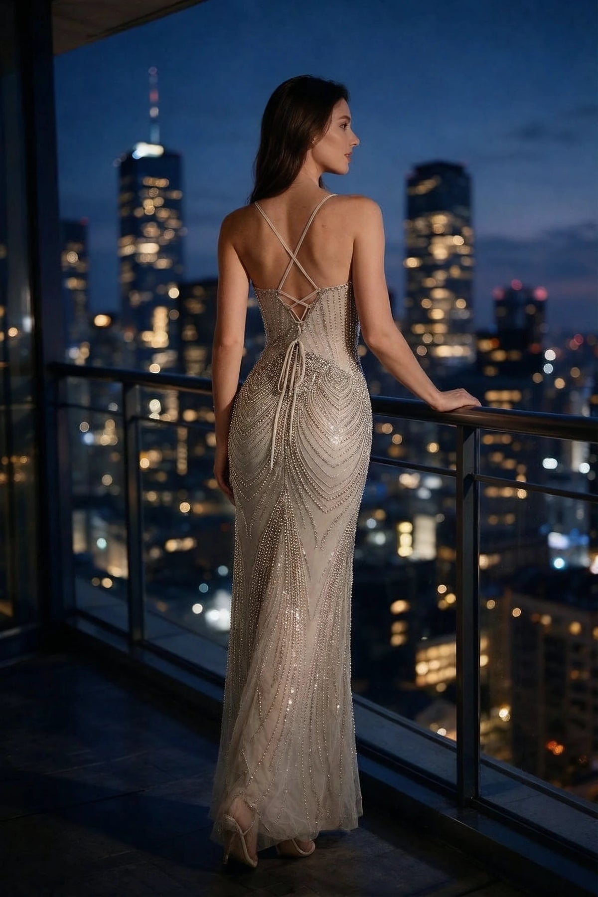 Rear view of the Augusta silver mermaid dress on a balcony, showing the open lace-up back.