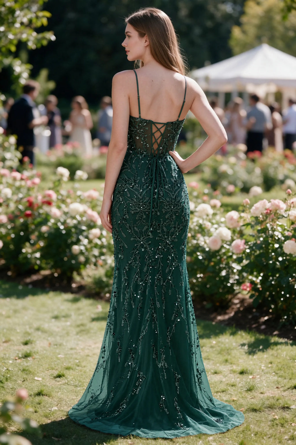 Rear garden view of Aurelia dark green mermaid dress with an open upper back and lace-up waist