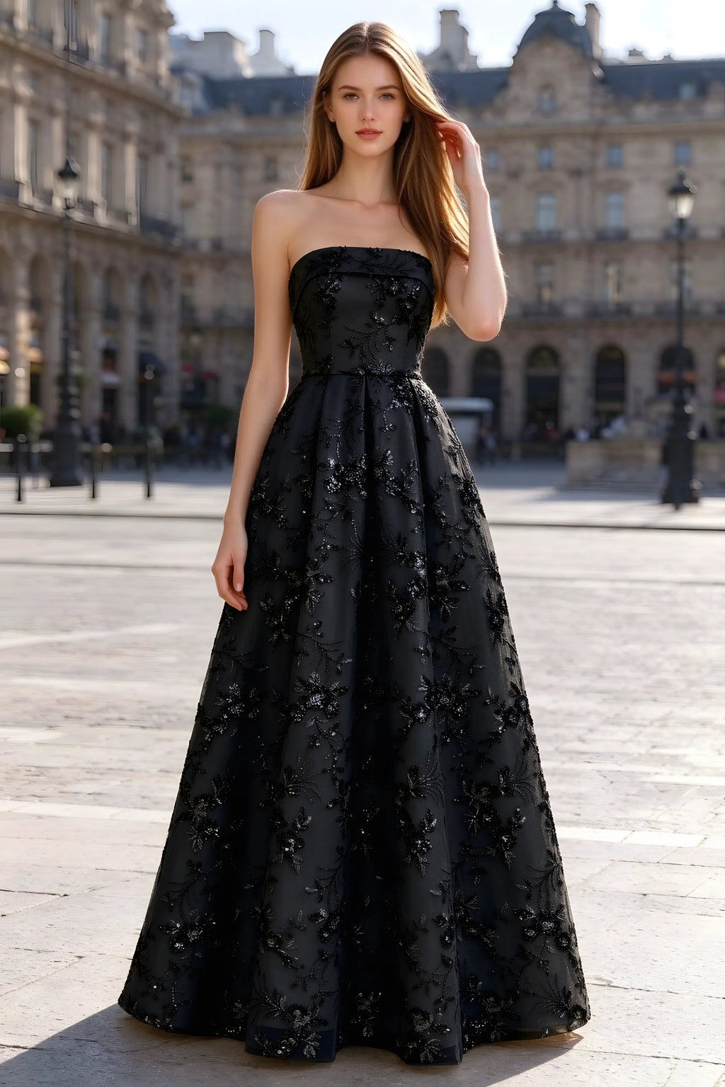 Avis black floral sequin A-line maxi dress shown from the front in a stone courtyard