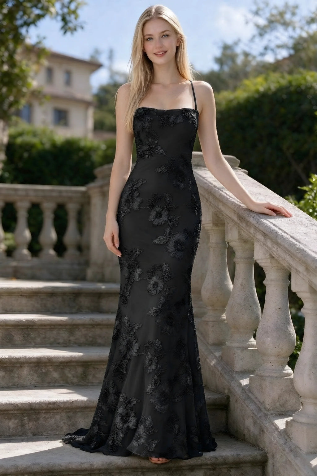 Outdoor front view of Belinda black floral lace mermaid dress on stone steps