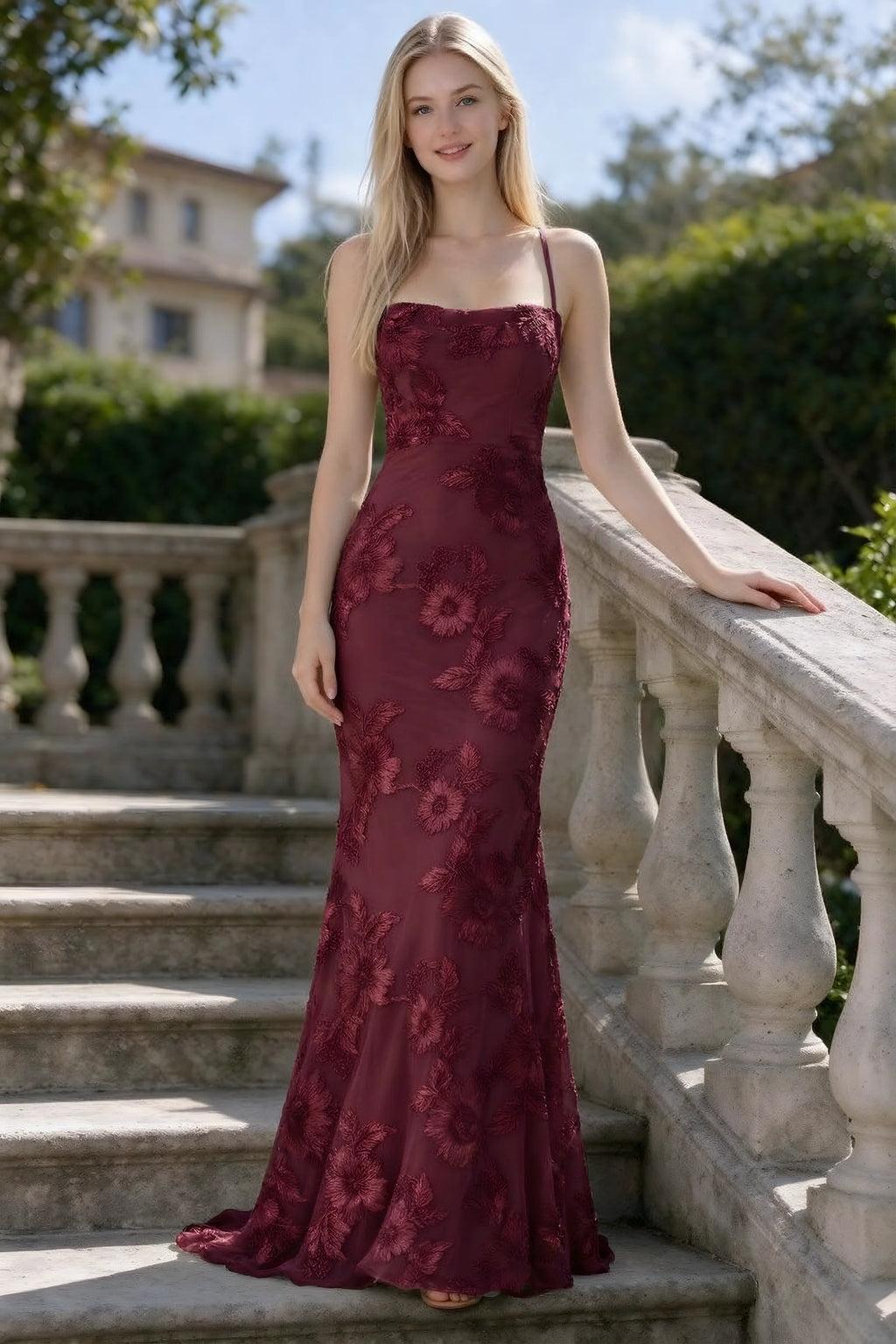 Outdoor front view of Belinda burgundy floral lace mermaid dress on stone steps