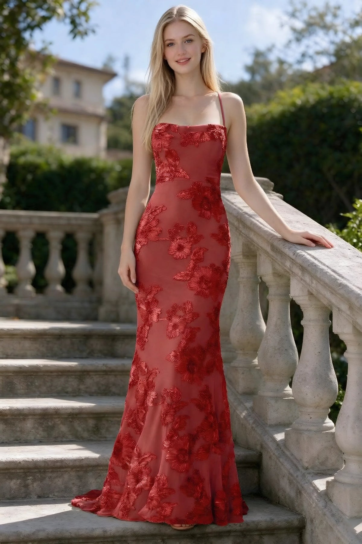 Outdoor front view of Belinda red floral lace mermaid dress on stone steps
