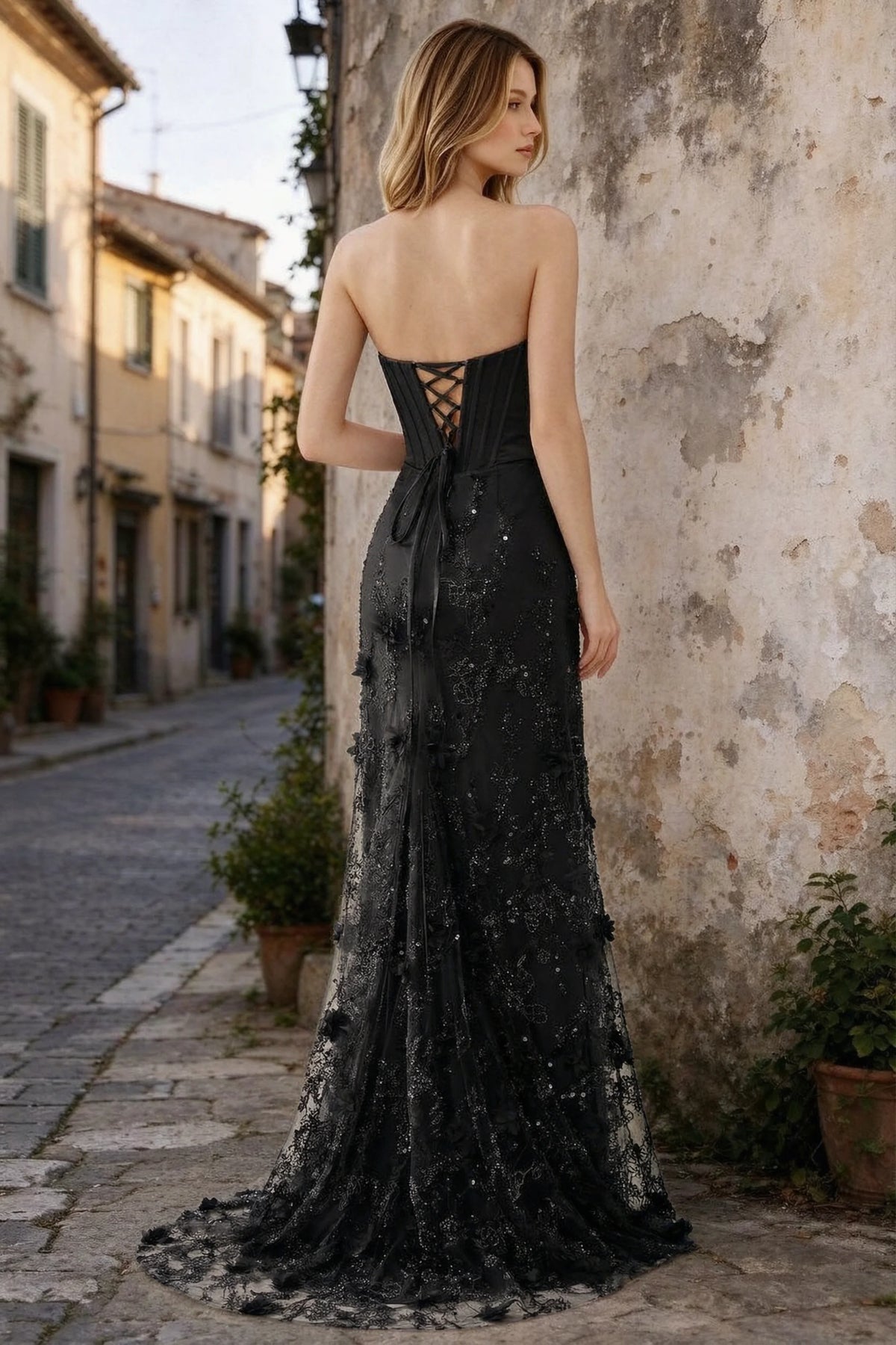 Outdoor rear view of Beth black maxi dress showing back lacing and the long embellished skirt