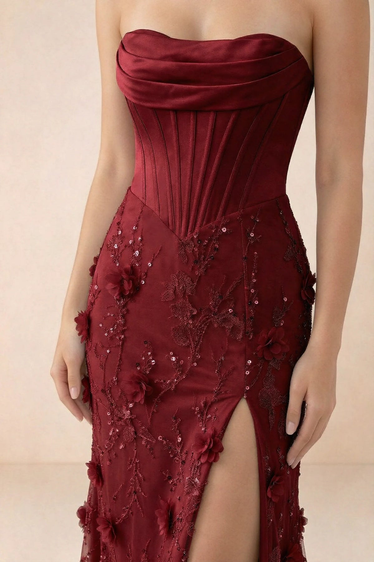 Close-up of Beth burgundy draped neckline, vertical corset panels and floral decoration above the slit