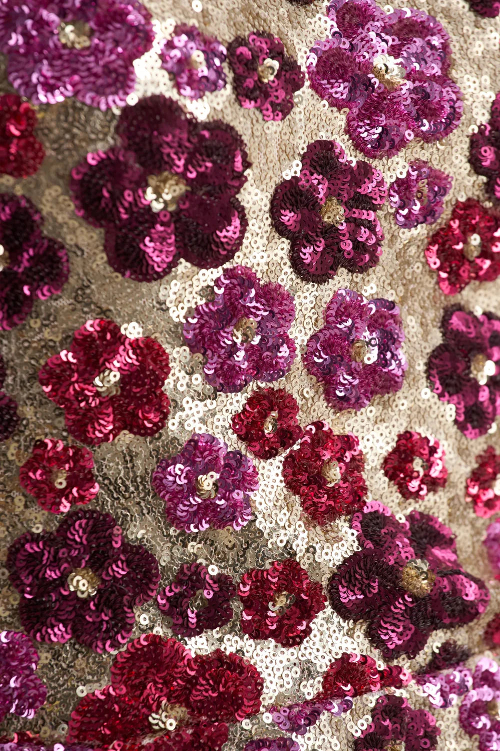 Macro shot of intricate floral sequin embroidery pattern on LVLVS Brooke dress, featuring fuchsia and burgundy flowers on gold mesh fabric