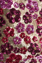 Macro shot of intricate floral sequin embroidery pattern on LVLVS Brooke dress, featuring fuchsia and burgundy flowers on gold mesh fabric