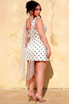 Back view of plus size woman in LVLVS Candice white polka dot dress showcasing the asymmetrical chiffon scarf hem
