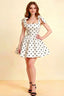 Elegant woman wearing LVLVS Cassandra white polka dot bow straps mini skater dress with square neckline in studio setting