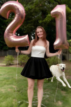 Real customer wearing LVLVS Catherine white and black bandeau dress celebrating a 21st birthday party outdoors with rose gold balloons and a pet dog.