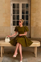 Summer brunch style LVLVS Celia olive green dress styled with white accessories, elegant plus size fit on bench for daytime party.