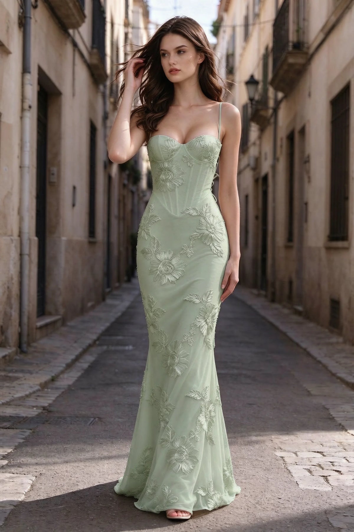 Outdoor front view on a city street of Celine sage green floral embroidered corset mermaid maxi dress with a long flared hem