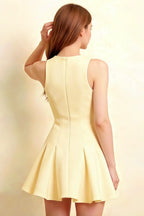 Rear view detail of the sleeveless Cheryl dress in lemon color showcasing the back zip fastening and pleated peplum hem.