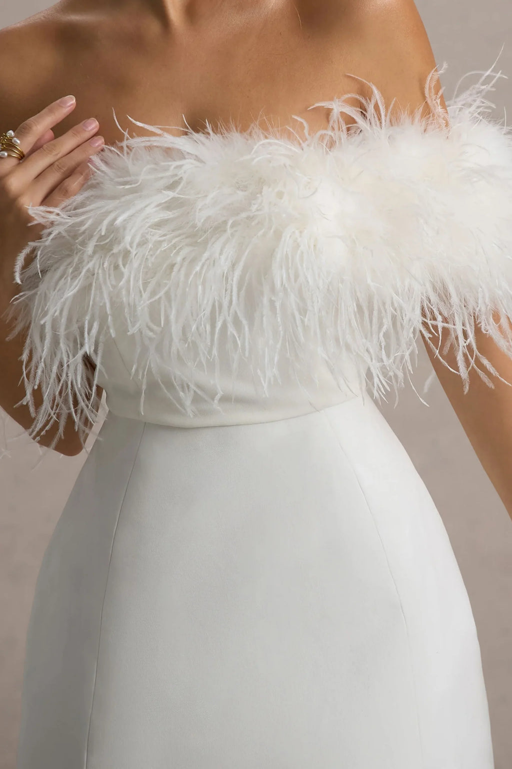Macro close-up of white feather trim on Chloe strapless mini dress, soft fluffy texture detail against skin, made with high-quality crepe fabric.
