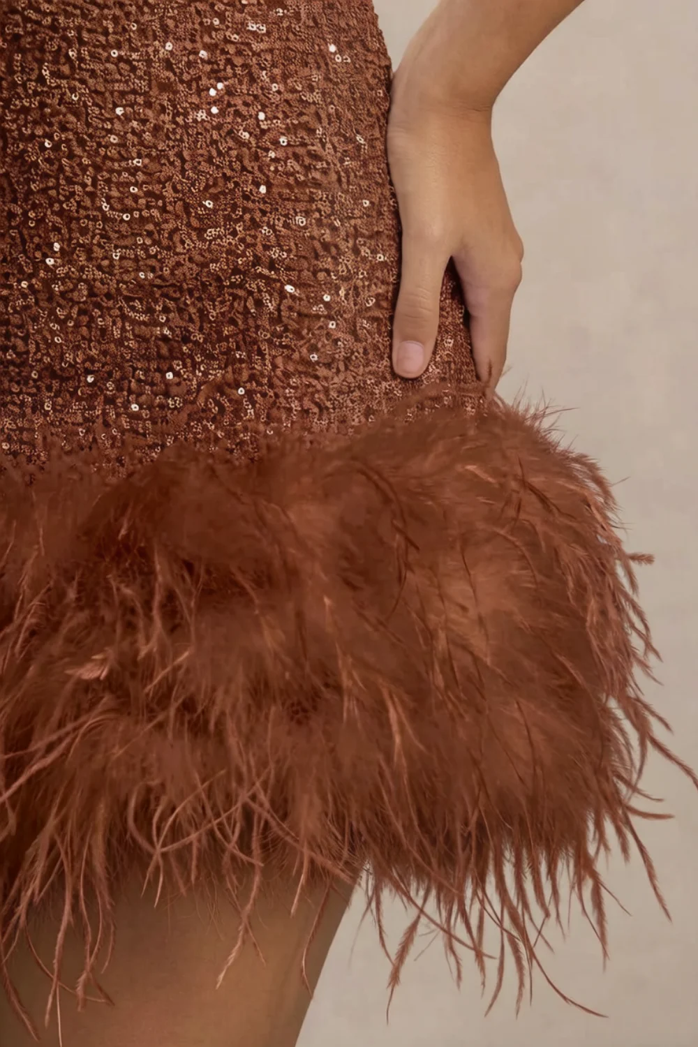 Detailed close-up of Christine brown sequin dress feather trim, focusing on texture and craftsmanship of the luxury sequin fabric.