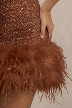 Detailed close-up of Christine brown sequin dress feather trim, focusing on texture and craftsmanship of the luxury sequin fabric.