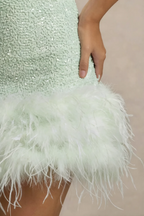 Close-up detail of Christine mint sequin dress feather trim, showcasing texture and craftsmanship of the hem.