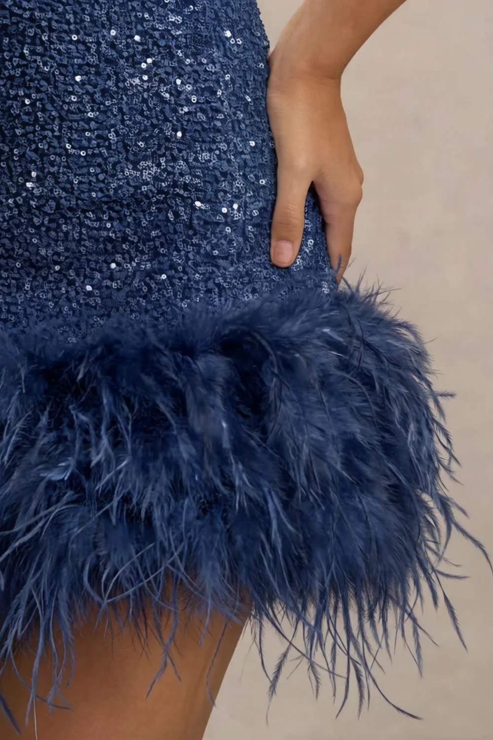 Detailed macro shot of Christine navy dress feather trim and sequin texture, close-up of the fluffy feathers and shiny fabric material for luxury party wear.