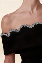 Extreme close up of the Christy dress showcasing the intricate silver rhinestone wave pattern along the off-shoulder neckline.