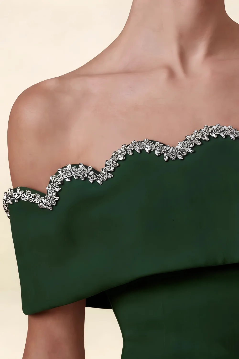 Macro detail of Christy dark green dress neckline, displaying the high quality crepe material and shimmering rhinestone wave pattern.