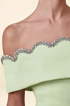 Macro close-up detail of the silver rhinestone scallop trim on the Christy mint off the shoulder dress, set against smooth crepe fabric.