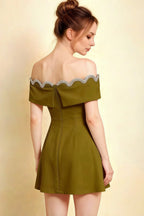 Side profile of olive off-shoulder mini dress, highlighting gathered waist and crepe fabric texture.