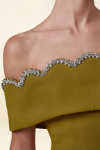 Macro close-up of olive crepe fabric and sparkling rhinestone off-shoulder neckline trim.