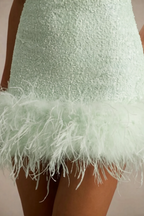 Extreme close-up detail of the Cindy mint sequin fabric texture and the soft feather trim at the hem, showcasing material quality.