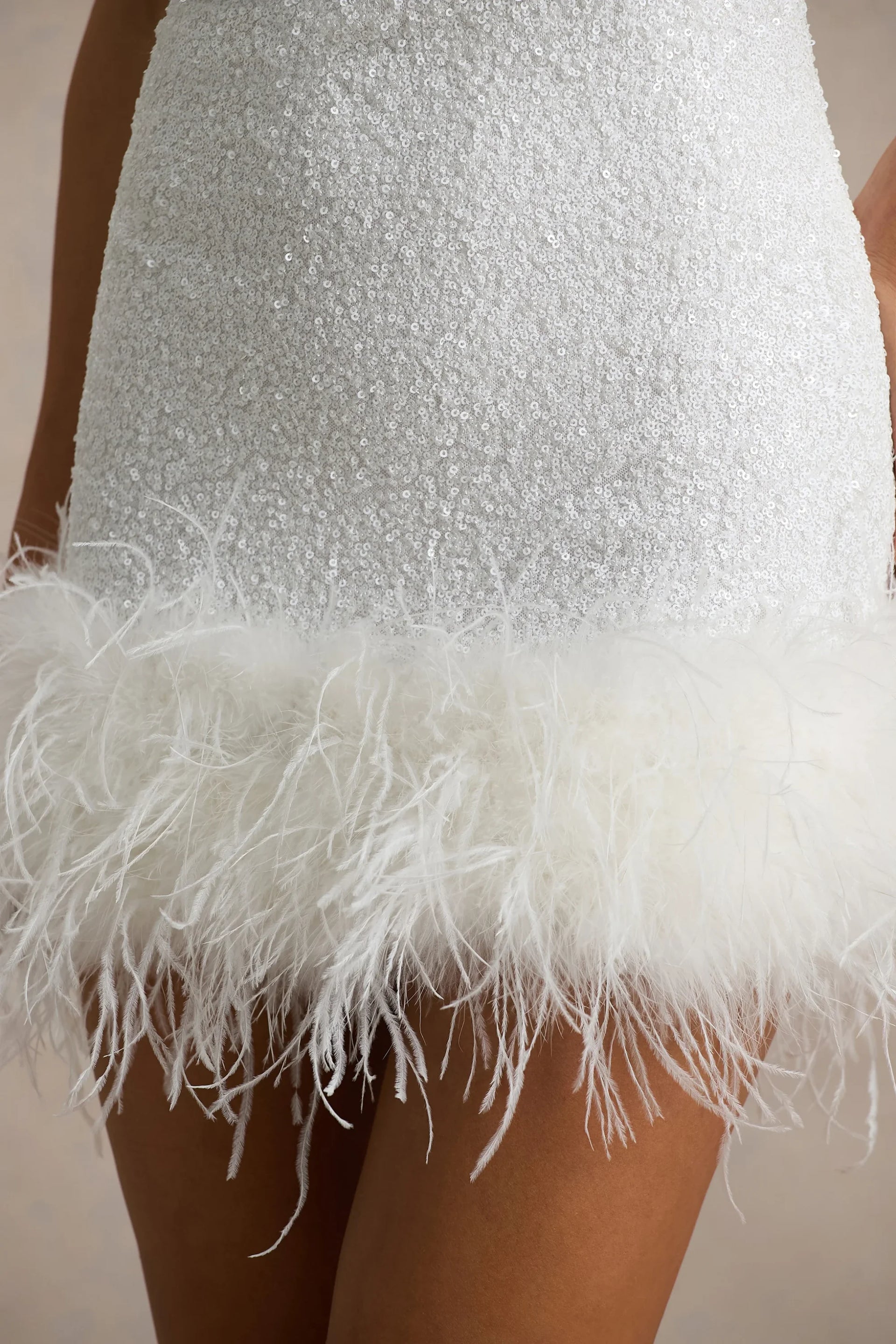 Close-up of Cindy white sequin dress feather trim and fabric texture, highlighting the quality and details of the material.