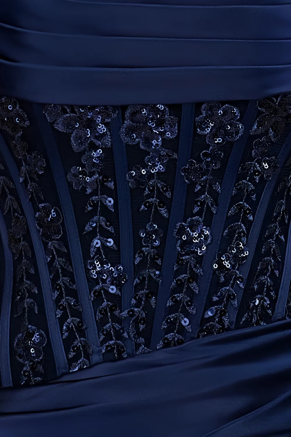 Close-up of Clara navy satin bodycon strapless mini dress bodice, showcasing intricate lace & sequin floral embroidery, vertical satin pleats, and smooth navy satin fabric details