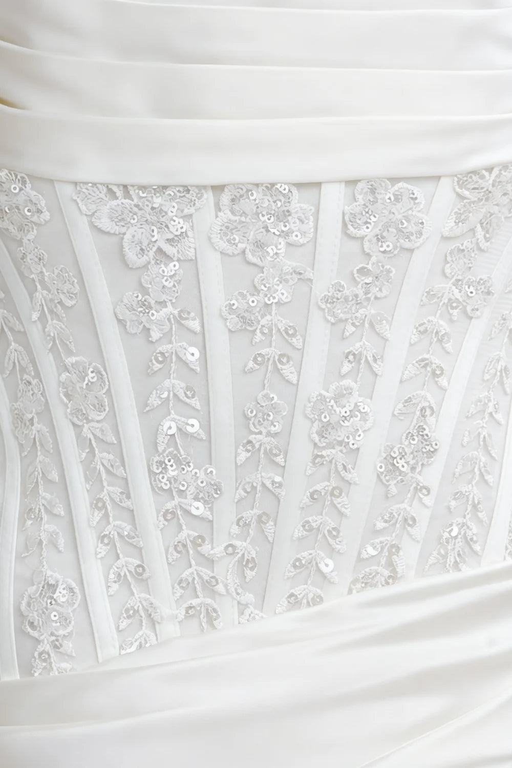 Clara white satin mini dress close - up: intricate lace appliqué with sequins, structured corset bodice detailing