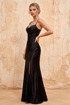 Woman wearing a black evening gown against a textured beige wall.