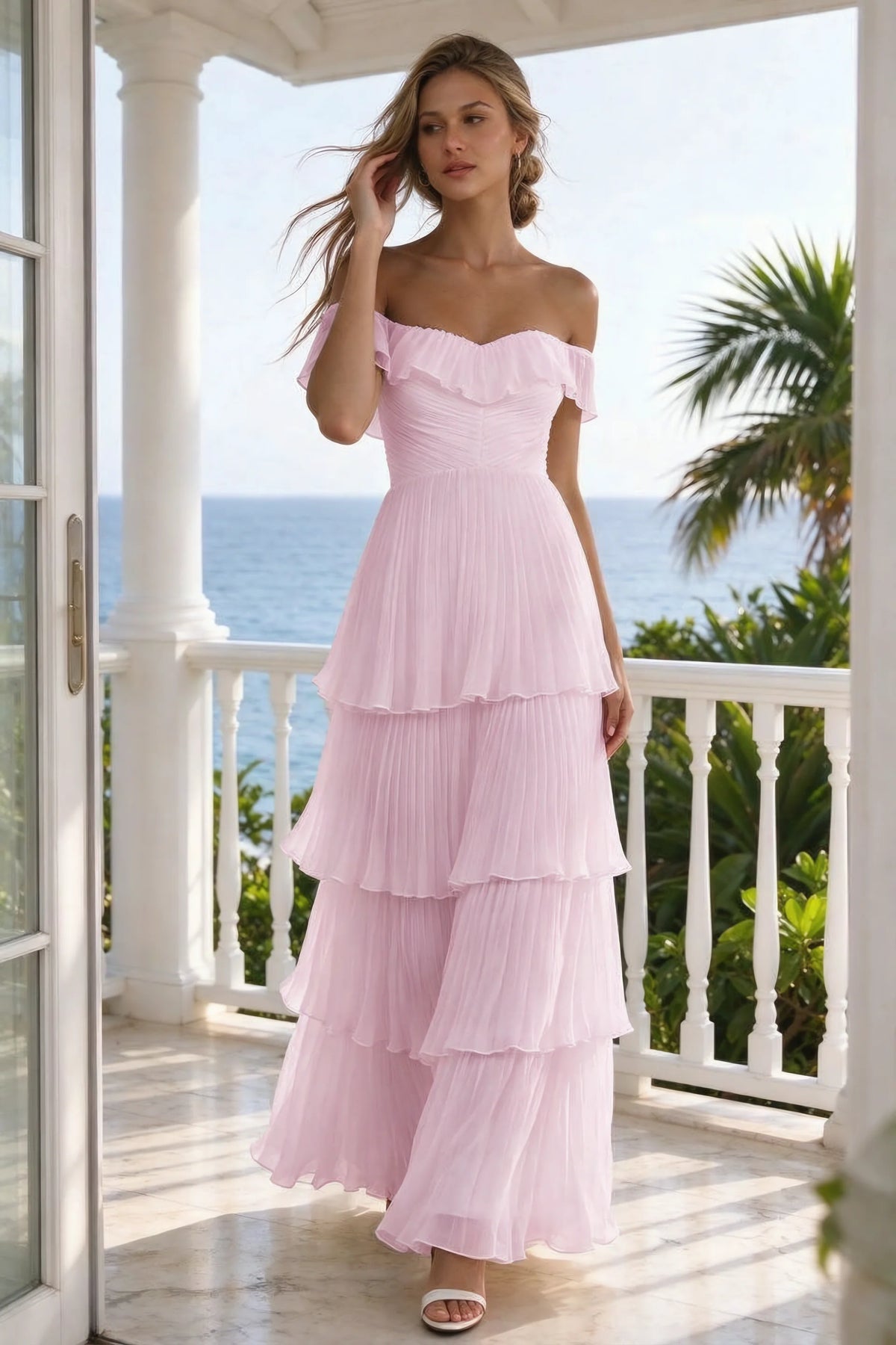 Outdoor front view on a seaside terrace of Seraphina candy pink tiered ruffle maxi dress with a long flowing skirt