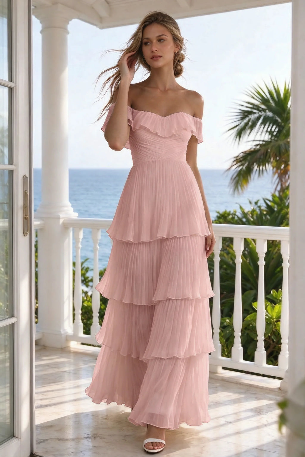 Outdoor front view on a seaside terrace of Seraphina light pink tiered ruffle maxi dress with a long flowing skirt