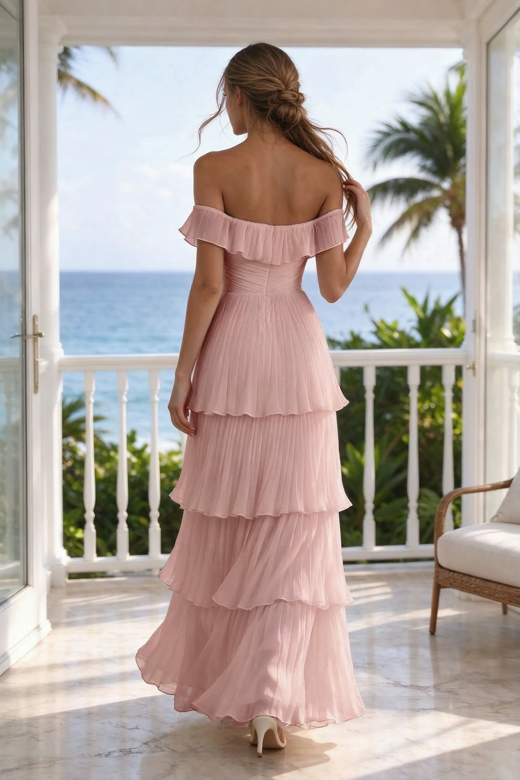 Outdoor rear view on a seaside terrace of Seraphina light pink tiered ruffle maxi dress with a long flowing skirt