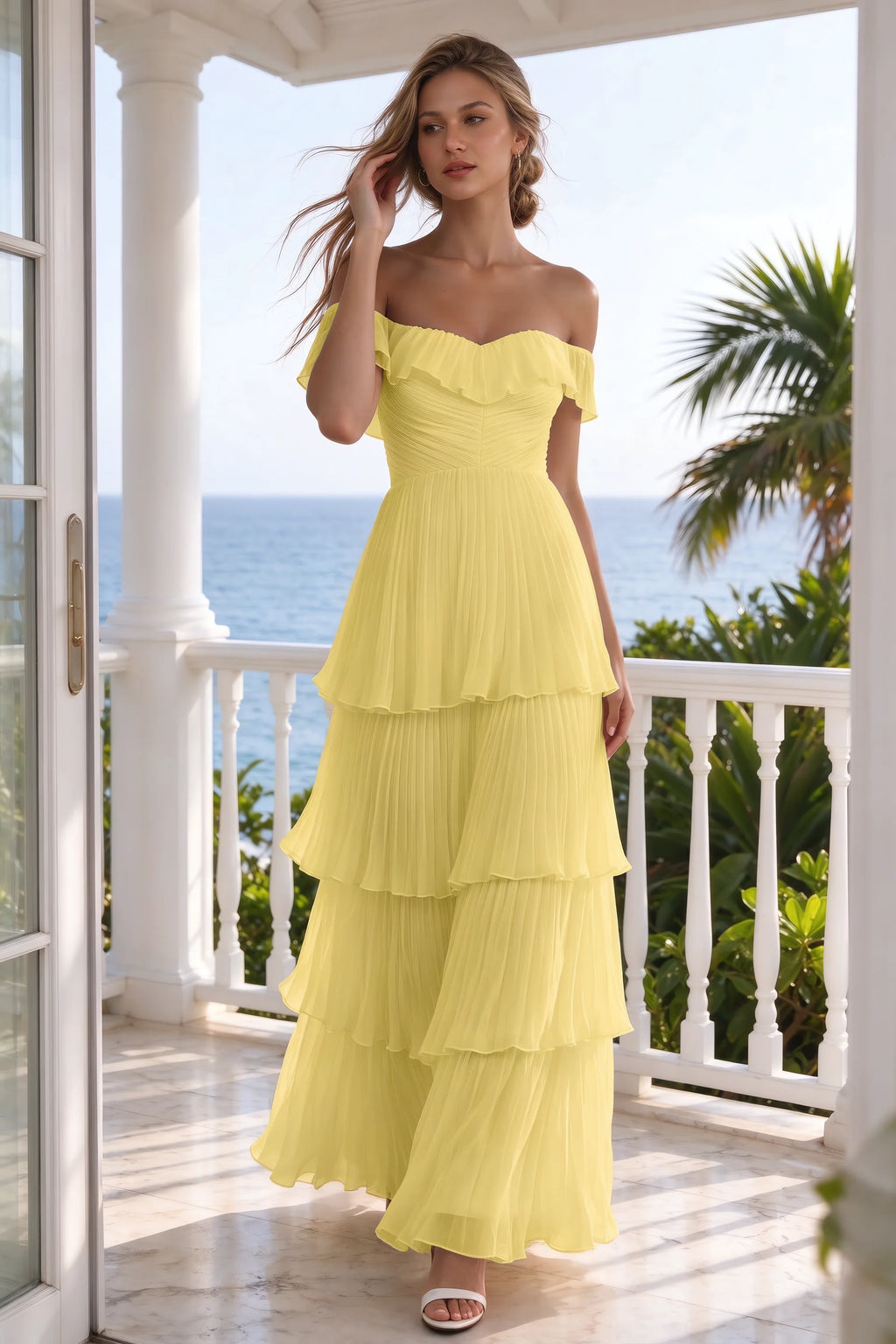 Outdoor front view on a seaside terrace of Seraphina pastel yellow tiered ruffle maxi dress with a long flowing skirt