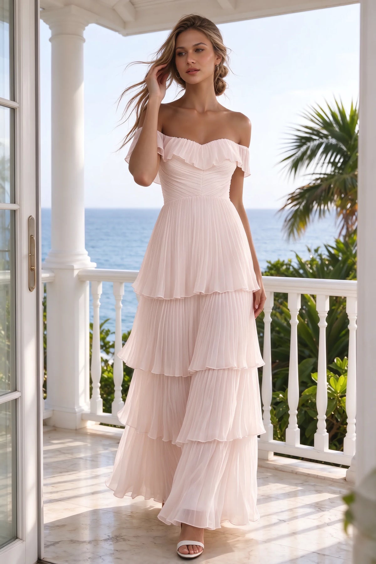 Outdoor front view on a seaside terrace of Seraphina powder pink tiered ruffle maxi dress with a long flowing skirt