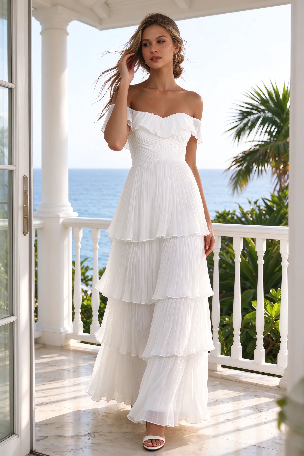 Outdoor front view on a seaside terrace of Seraphina white tiered ruffle maxi dress with a long flowing skirt